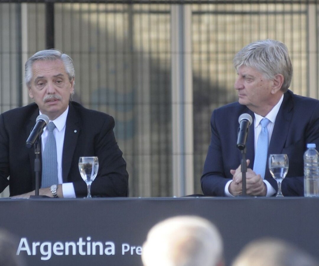 Dos dirigentes de traje sentados ante micrófonos en una conferencia, con un cartel que dice Argentina