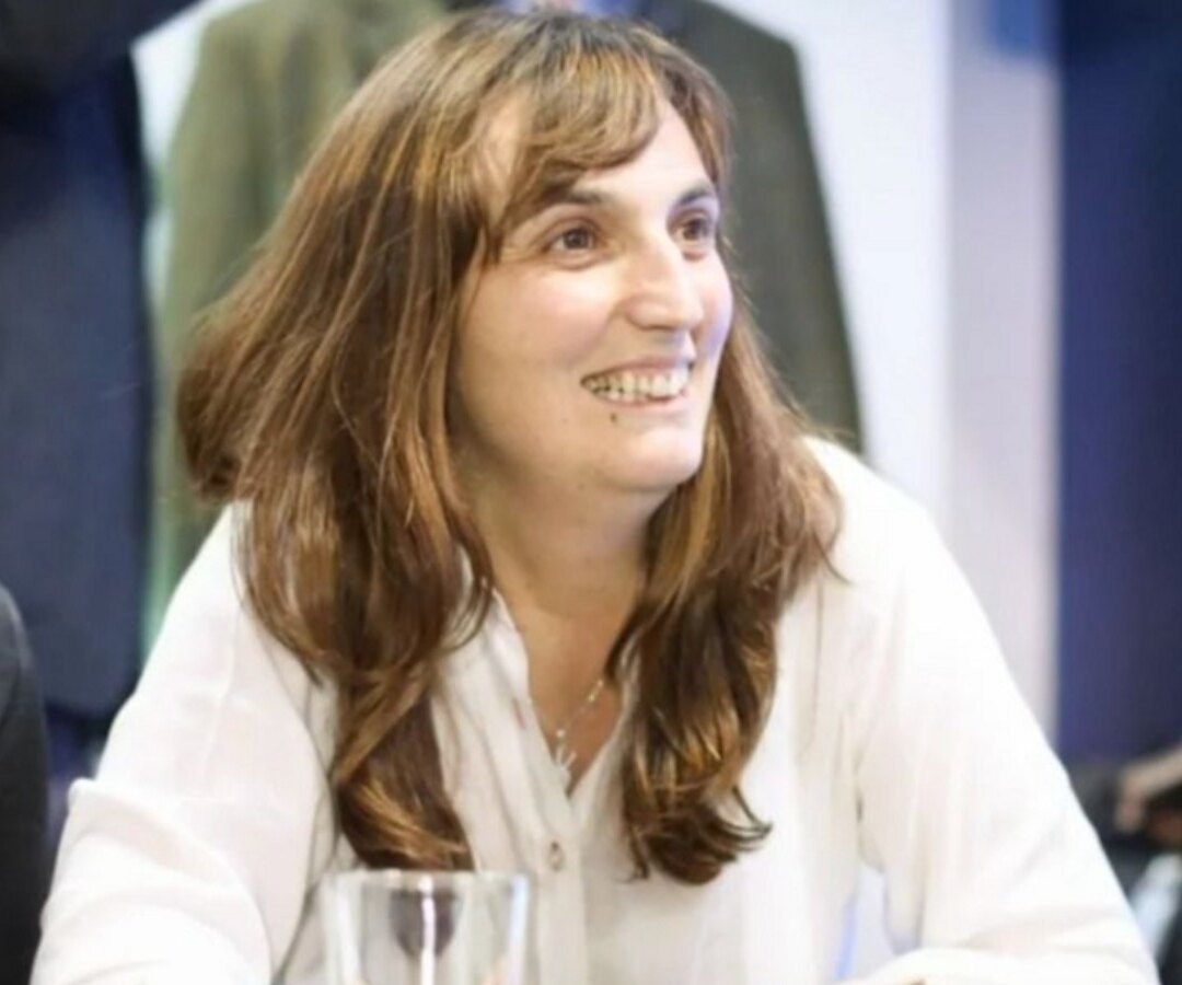 Dirigente pampeana sonríe durante un acto político, sentada a una mesa junto a otras personas