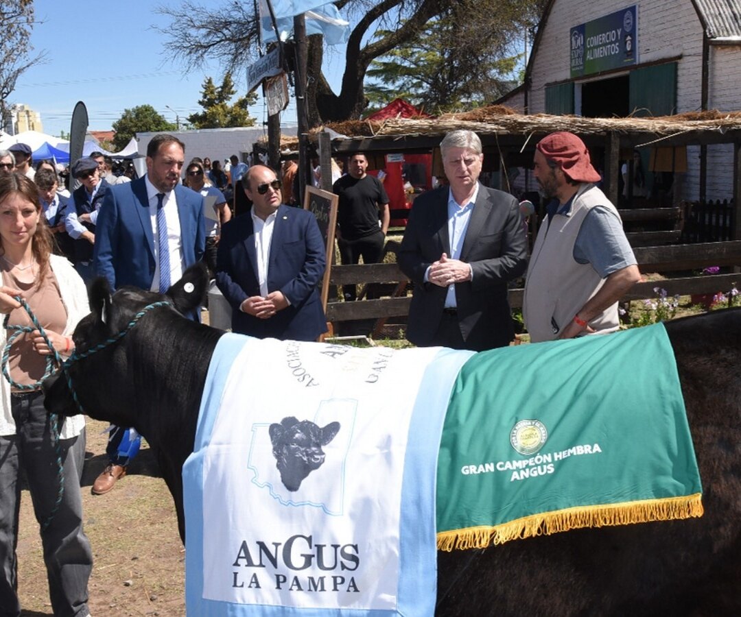 Una mujer sostiene a un ternero Angus premiado junto a autoridades en la Expo Rural de Santa Rosa