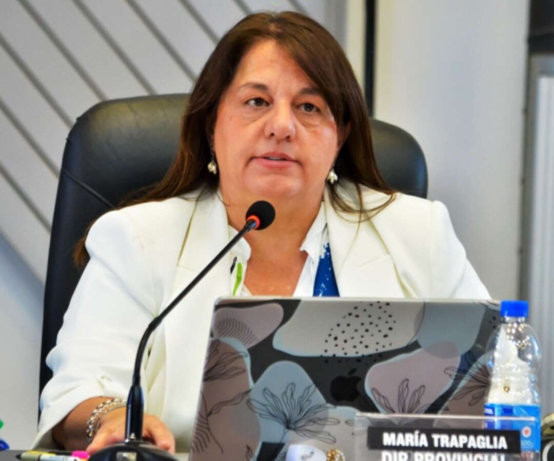Mostrador de una farmacia: una persona mayor entrega una receta en papel a un farmacéutico que consulta una computadora